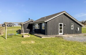 A black wooden building with a porch, a swing set, and a number 22 sign. - Amazing home in Nordborg with sauna (Nordborg)