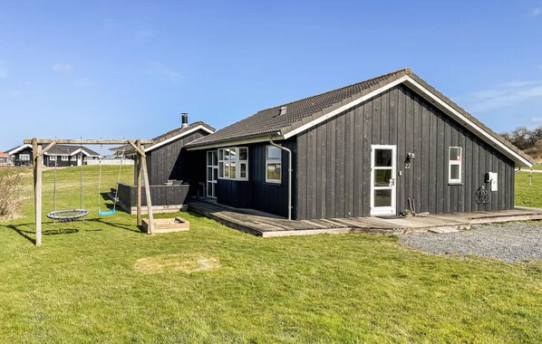 A black wooden building with a porch, a swing set, and a number 22 sign. - Amazing home in Nordborg with sauna (Nordborg)