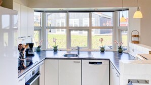 Une cuisine moderne dotée d’une baie vitrée, d’un four encastré et d’un lave-vaisselle.