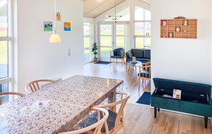 A spacious living area with a dining table, chairs, a sofa, and a coffee table. There are large windows allowing natural light and views of the outdoors. - Amazing home in Nordborg with sauna (Nordborg)