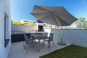An outdoor patio with a table, chairs, and a large umbrella.