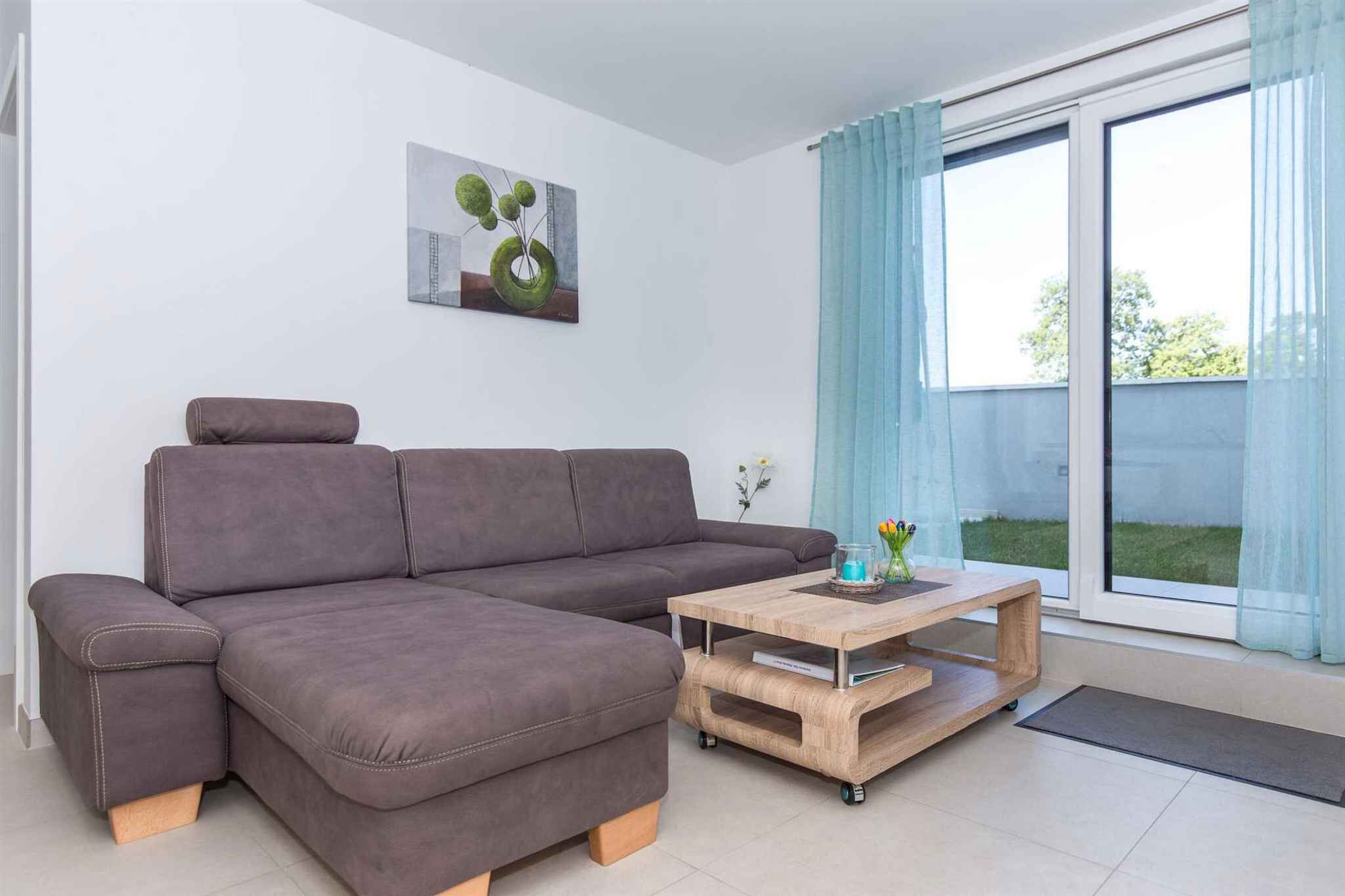 A modern living room with a sectional sofa, a wooden coffee table, and a large window with curtains.