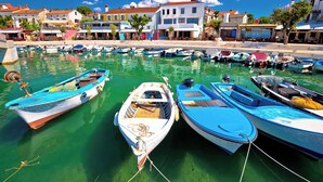 A marina with several boats docked, a clear blue sky, and buildings in the background.