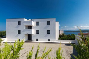Un bâtiment moderne doté d’un toit plat, de nombreuses fenêtres et d’une zone pavée à l’avant.
