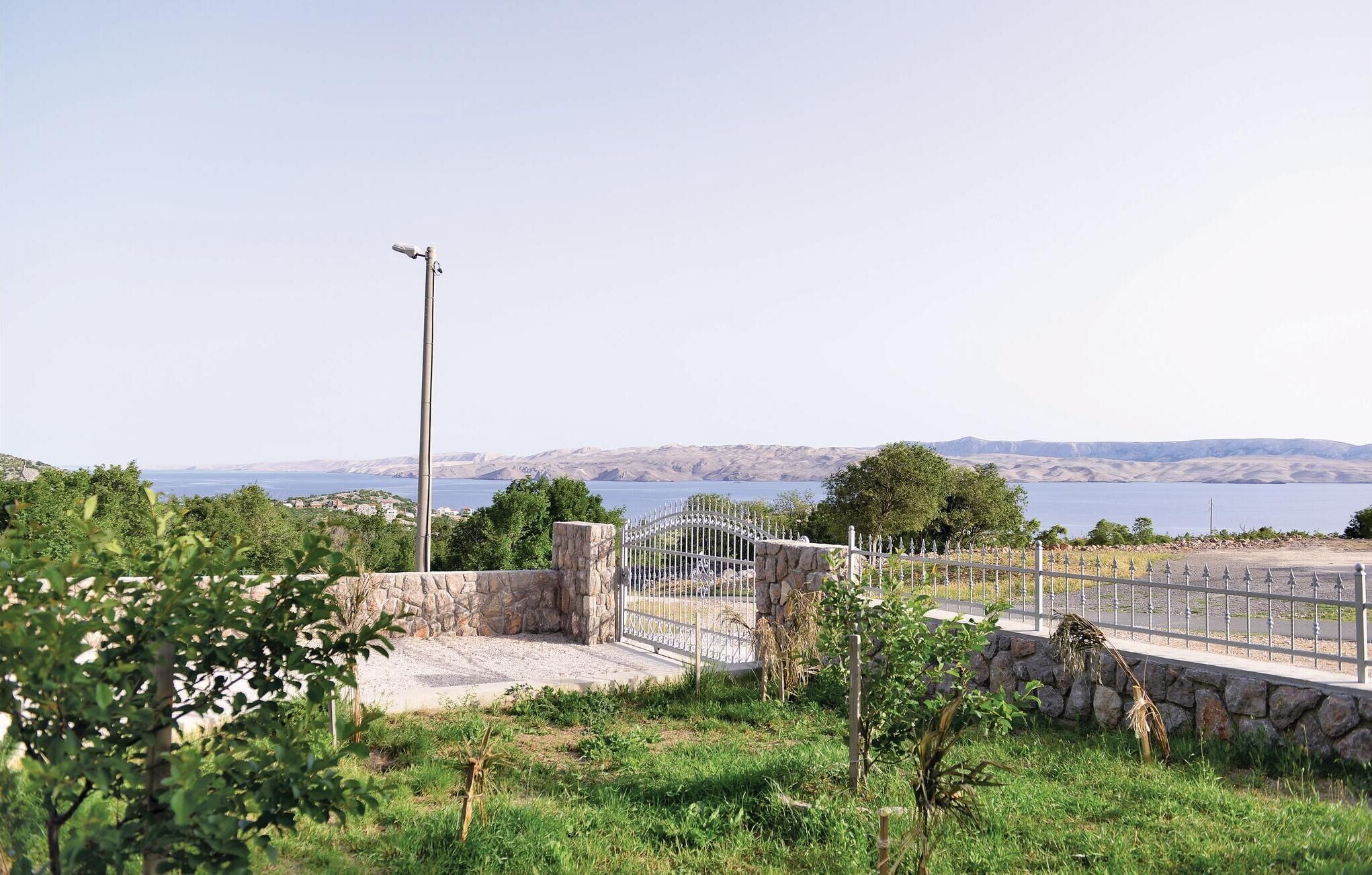 Un paysage côtier avec une porte en pierre, une clôture en métal et une caméra de surveillance.
