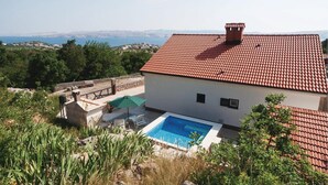 Eine Villa mit Swimmingpool, rotem Ziegeldach und Meerblick.