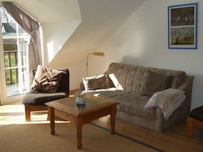 Un salon confortable avec un canapé, un fauteuil, une table et une lampe.