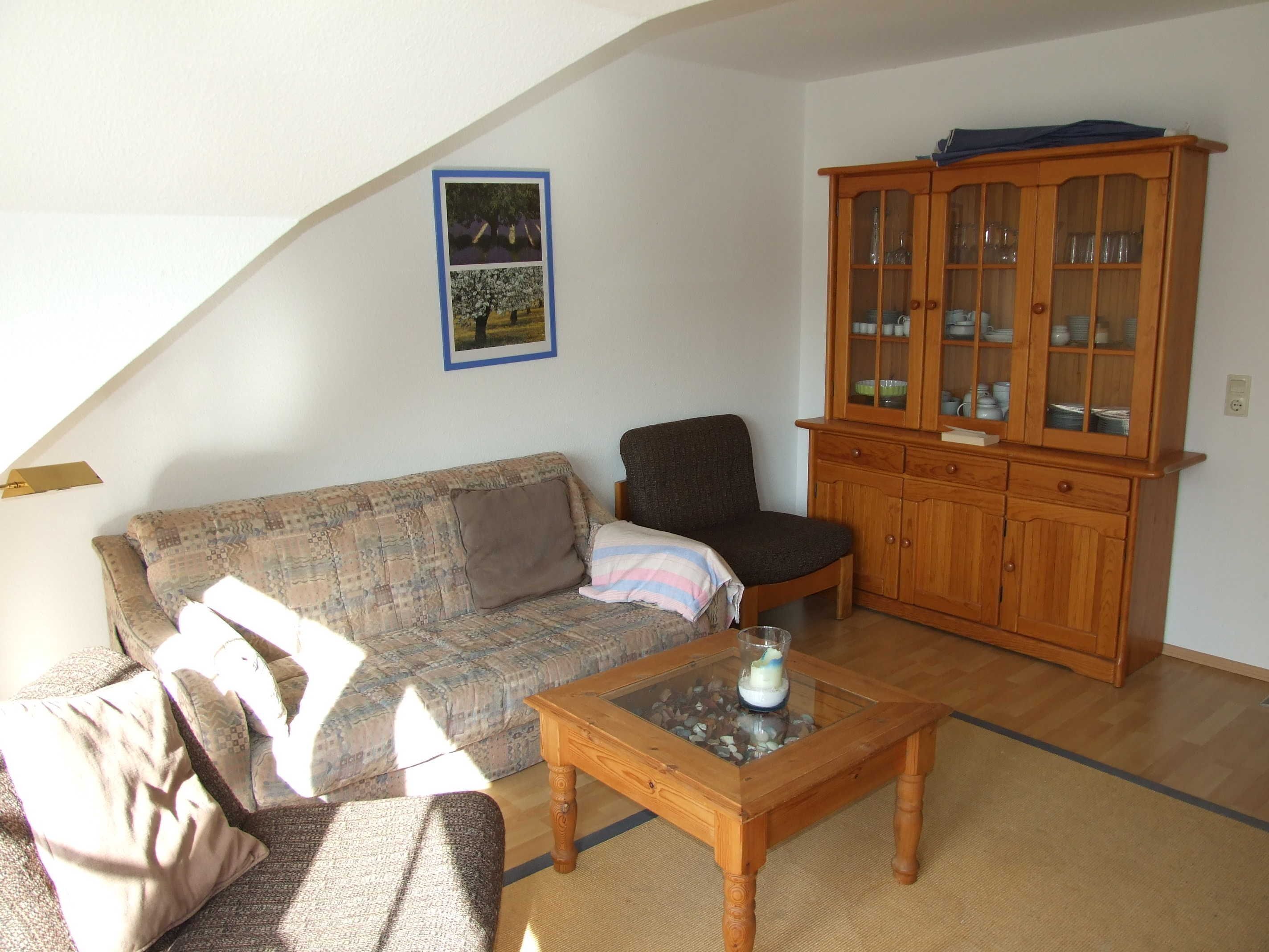 A living room with a sofa, armchair, coffee table, and wooden cabinet.
