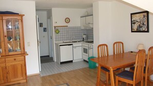 A compact kitchen with white cabinets, a coffee maker, and a clock on the wall.