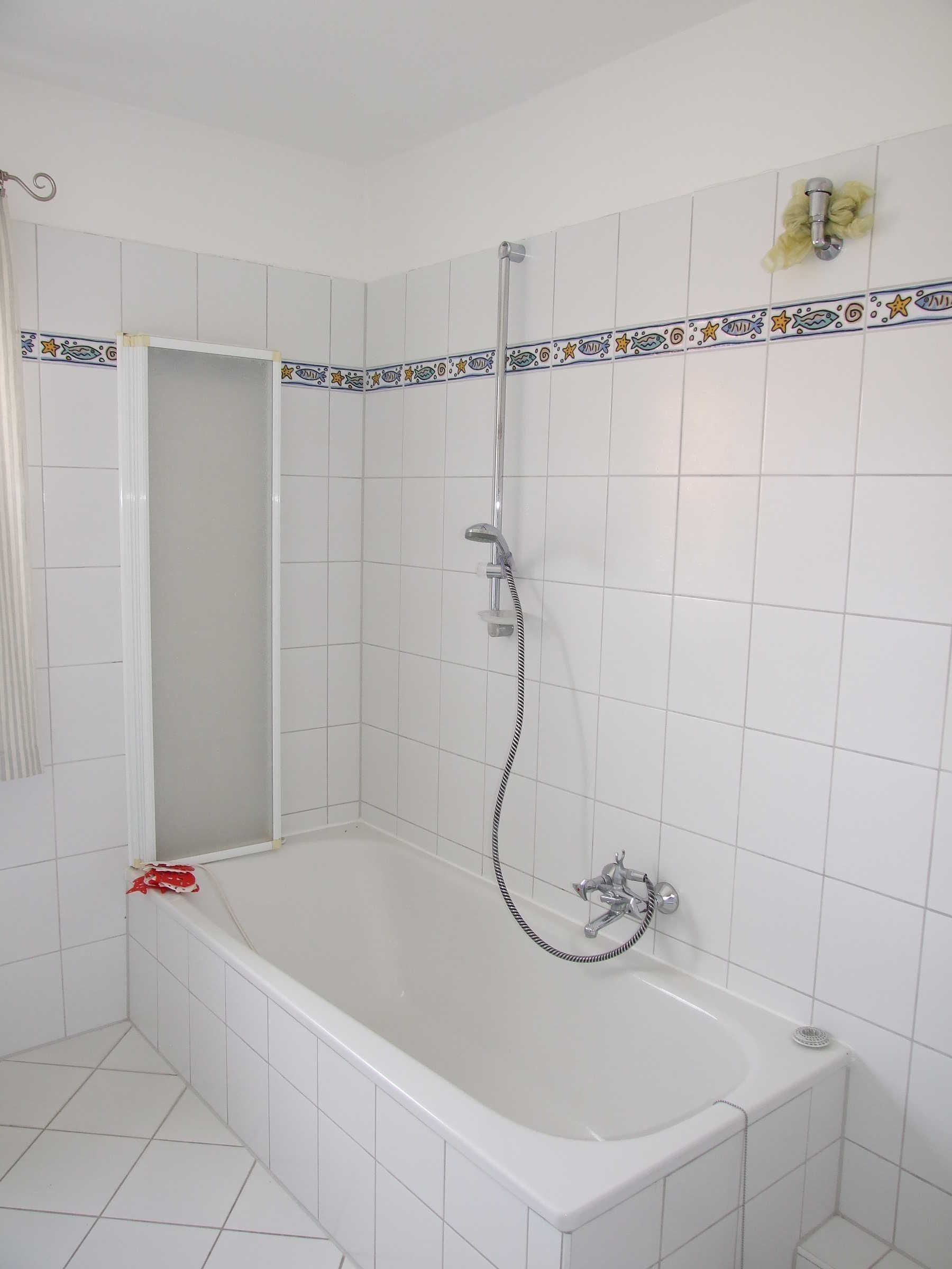 Un baño con bañera, ducha y paredes de azulejos.