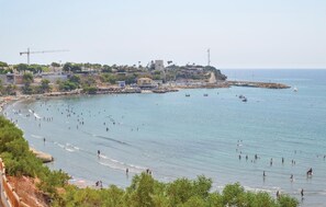 A coastal area with a beach, boats, and a distant cityscape. - Beach front apartment in Orihuela Costa with WiFi (Orihuela Costa)