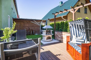 Un patio con una parrilla, mobiliario exterior y una pérgola.