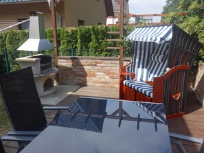 Une terrasse extérieure équipée d’un barbecue, de sièges et d’une structure en forme de pergola.