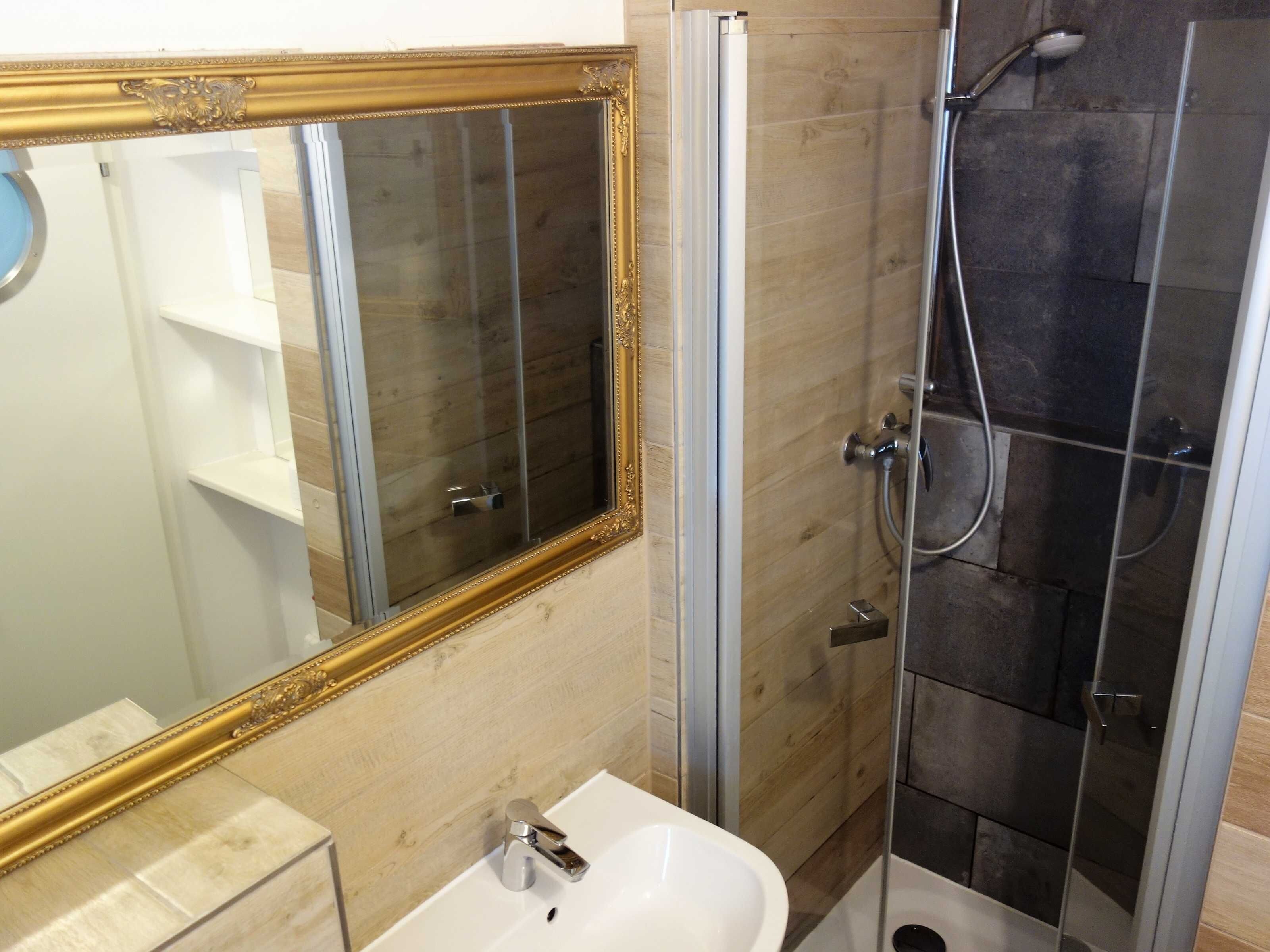 Een badkamer met een grote spiegel, een wastafel en een douchecabine.
