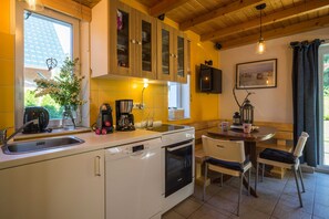 Une cuisine équipée d’un lave-vaisselle, d’un four et d’un coin repas avec une table et des chaises.