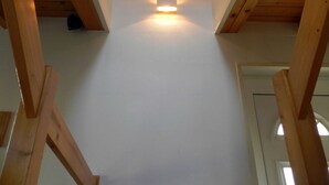 A high ceiling with wooden beams, a central light fixture, and a door at the end.