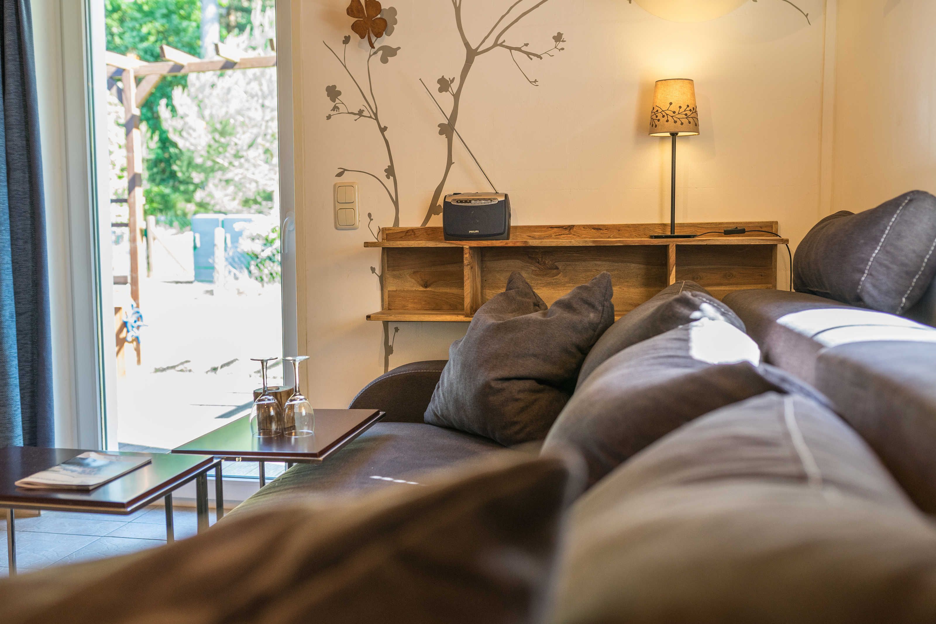 Ein modernes Wohnzimmer mit einer Couch, einem Tisch mit einem Buch, einer Lampe und einem Radio.