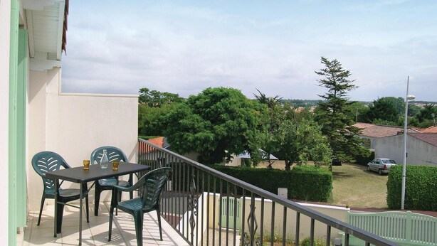 A balcony with a table and chairs, a view of a residential area, and a clear sky. - Lovely apartment in Vaux sur Mer (Vaux sur Mer)