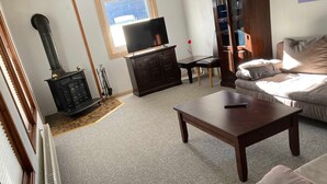 A living room with a sofa, a wooden coffee table, a TV on a stand, a fireplace, and a window.