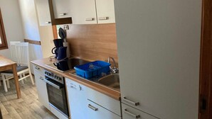 A compact kitchen with a dishwasher, oven, and a coffee maker on the counter.