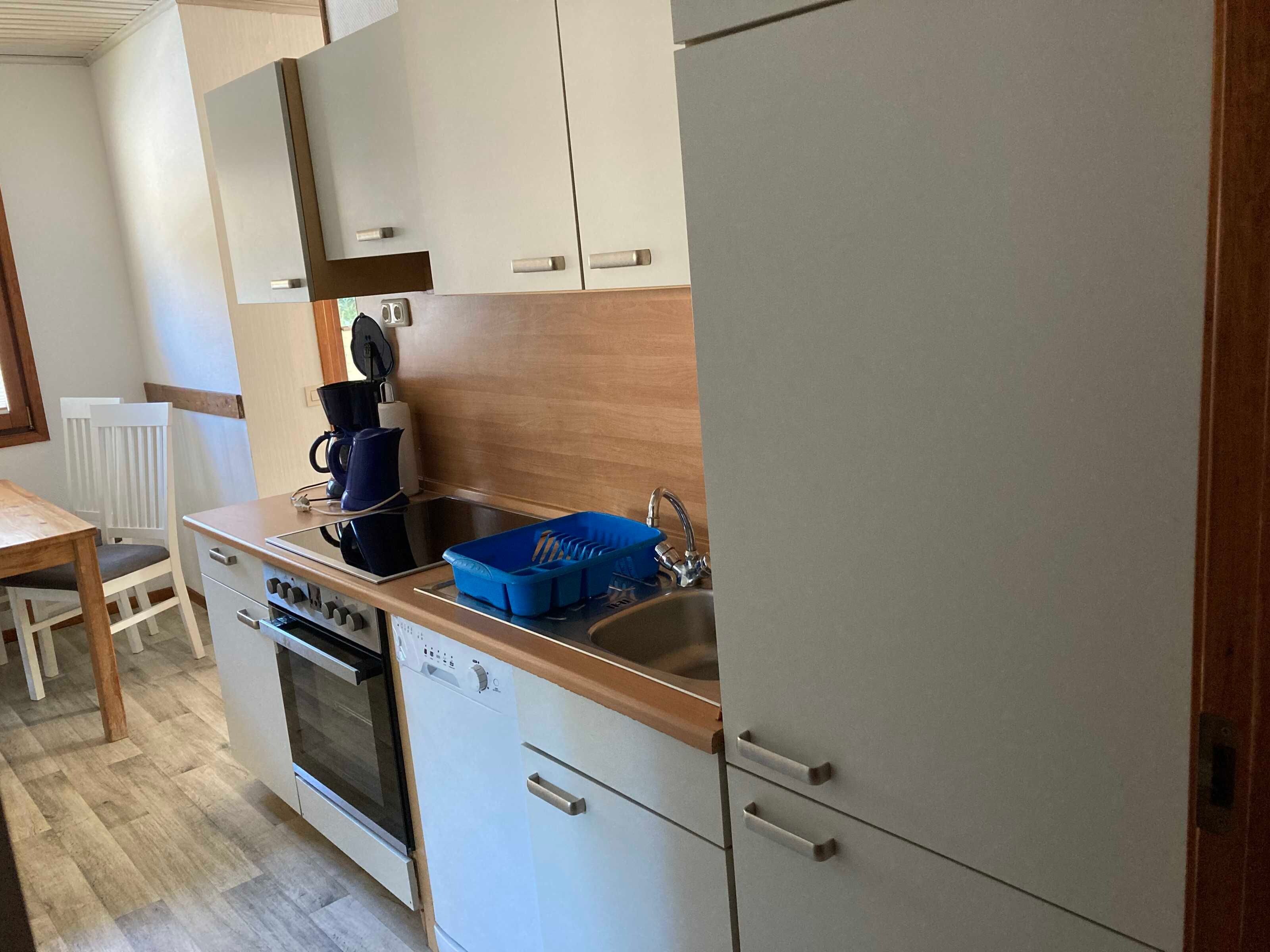 A compact kitchen with a dishwasher, oven, and a coffee maker on the counter.