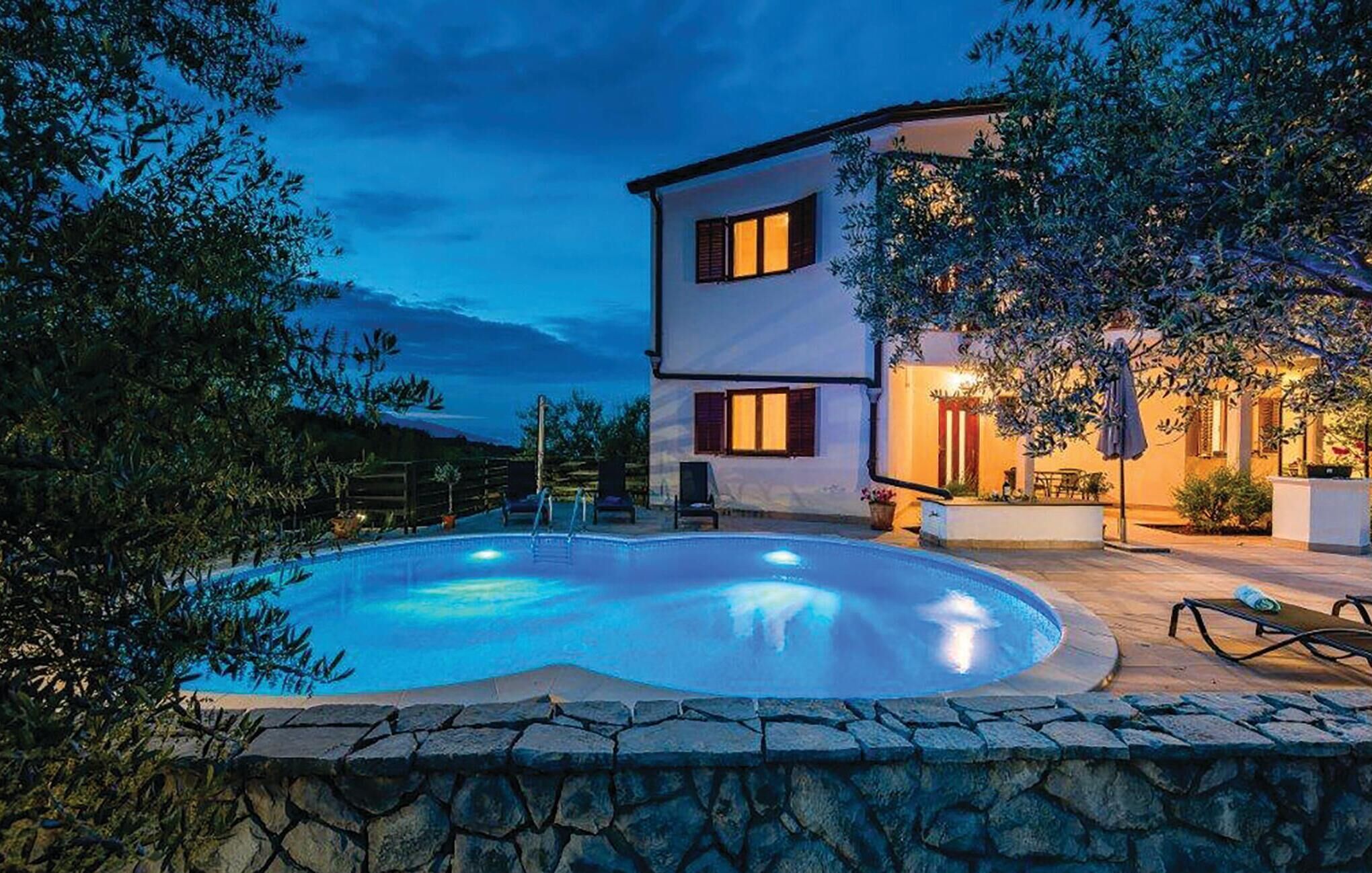 Ein zweistöckiges Haus mit Swimmingpool, Steinmauer und Gartenmöbeln.