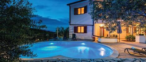 Ein zweistöckiges Haus mit Swimmingpool, Steinmauer und Gartenmöbeln.