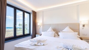 Una habitación de hotel con una cama grande, dos mesitas de noche y un ventanal con cortinas.