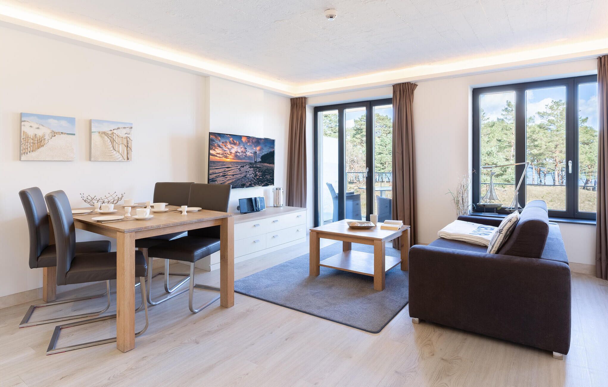 A modern living room with a dining area, large windows, and artwork on the walls.