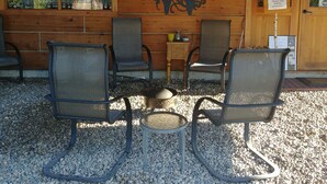 An outdoor seating area with four chairs and a table, wooden walls, and a sign reading "I.A. Wolfwood". - Wolfwood Guest Ranch (Clearwater)
