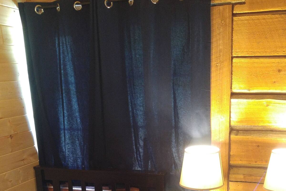 Ett mysigt rum med en säng, ett nattduksbord med en lampa och en sänggavel i trä.
