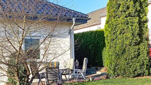 A house with a tiled roof, a well-maintained garden, and a neatly trimmed hedge.