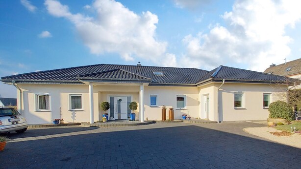 A two-story house with a tiled roof, a front porch, and a driveway.