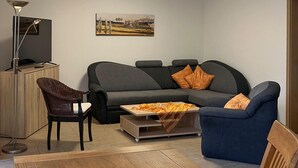 A living room with a sofa, two chairs, a coffee table, and a TV on a cabinet.