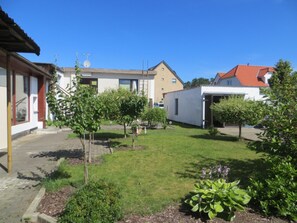 Een woonwijk met een verzorgd gazon, enkele kleine bomen, en verschillende gebouwen, waaronder een huis met een rood dak en een witte garage.