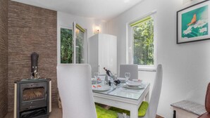 Un comedor con una mesa lista para dos, una chimenea y una ventana que da a zonas verdes.