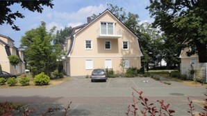 Een huis met twee verdiepingen en een oprit waar een auto geparkeerd staat.