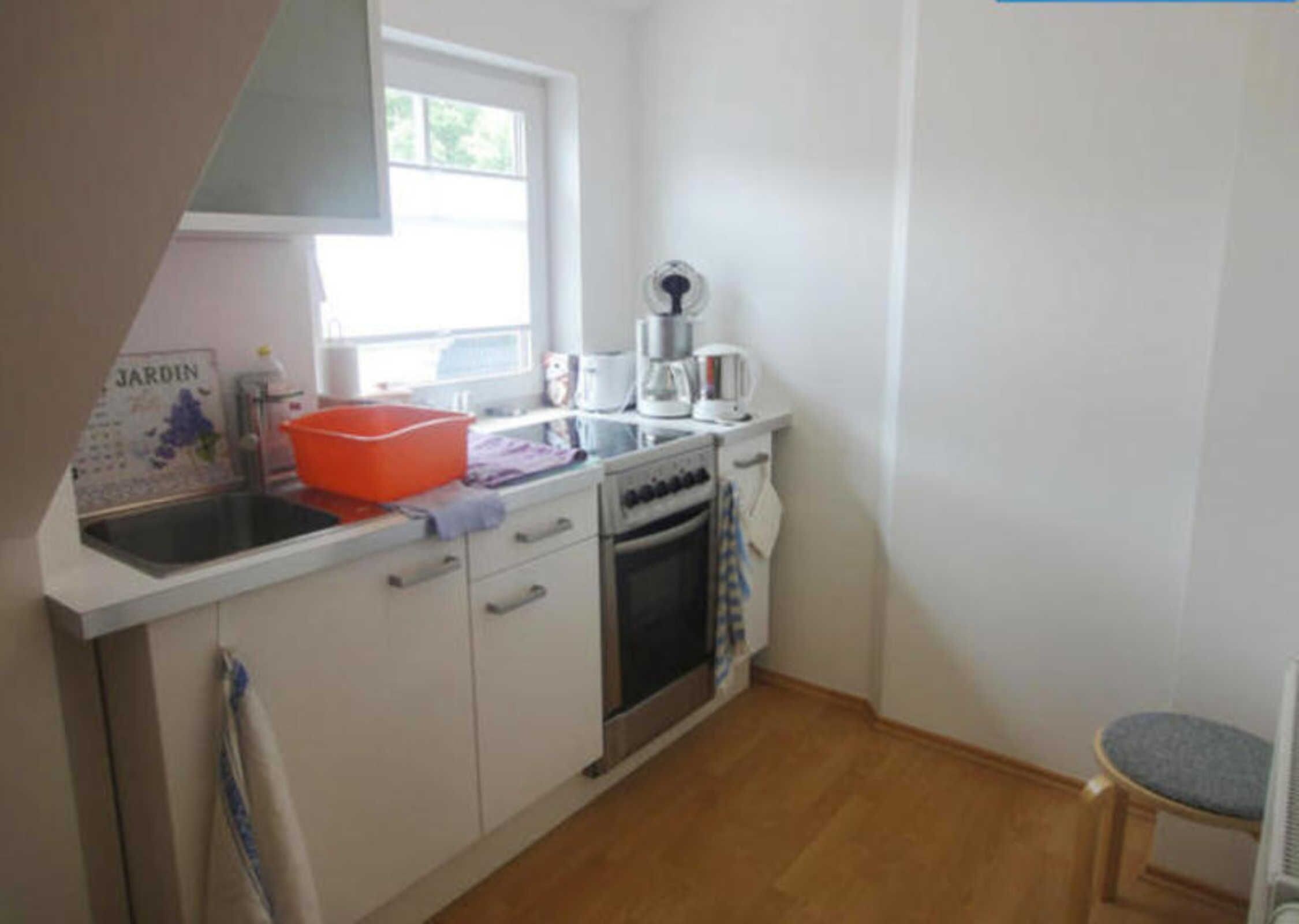 A compact kitchen with a sink, stove, and a window.