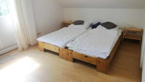Een kamer met een houten bed, een nachtkastje en een raam met gordijnen.