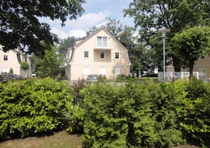 Ein zweistöckiges Haus mit Satteldach, umgeben von dichtem Grünwerk.