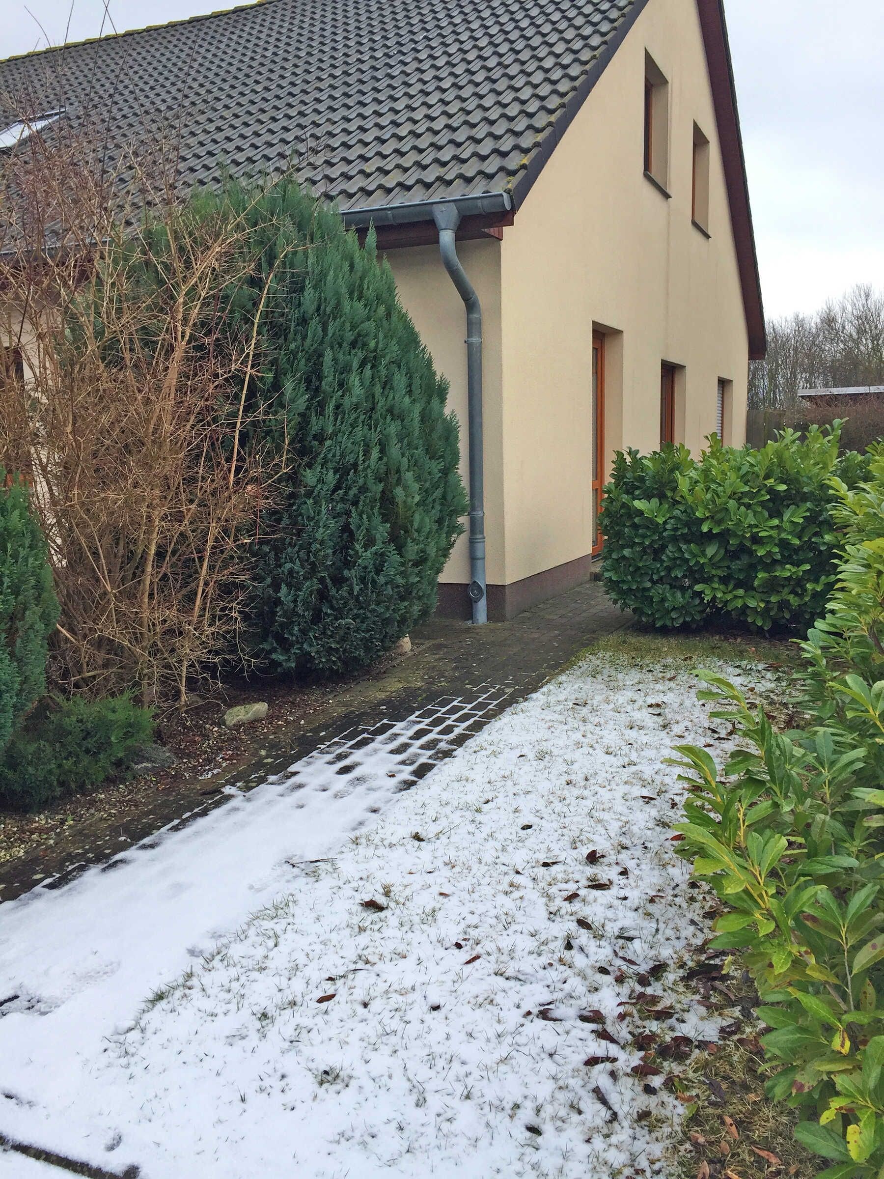 A house with a tiled roof, a gutter, and a snow-covered pathway.