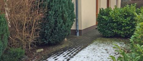A house with a tiled roof, a gutter, and a snow-covered pathway.