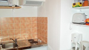 Una kitchenette compacta con estufa, pileta, microondas y cafetera.