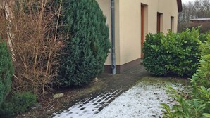 Una casa con techo de tejas, canalón y un sendero cubierto de nieve.