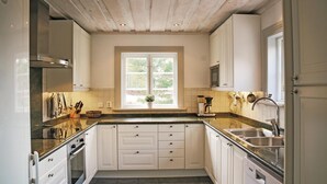Een keuken met witte kastjes, een raam, een fornuis en een gootsteen.