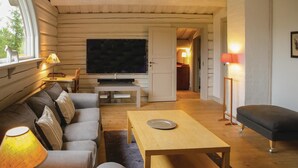 Een gezellige woonkamer met een bank, een televisie, een houten tafel en een lamp.