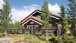 Een vakantiehuisje van hout met een steil dak, een veranda en een stenen fundering.