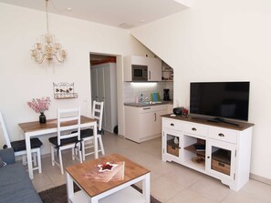 Una cocina moderna con armarios blancos, un microondas y un televisor de pantalla plana grande sobre un mueble de madera.