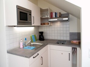 A compact kitchen with white cabinets, a stainless steel microwave, a coffee maker, and a sink. - beach street 14-09 . - 14-09 (Kühlungsborn)