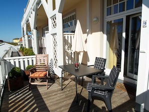 A covered outdoor seating area with a table and chairs, a white fence, and a building with a number '9' sign.